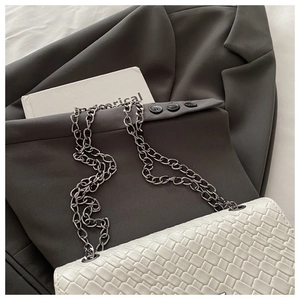 Vue détaillée du sac à bandoulière blanc avec texture tressée et chaîne sombre