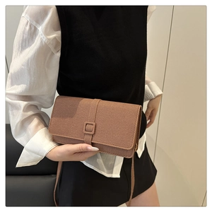 Détail d'un sac bandoulière marron vintage avec texture diagonale et boucle carrée chic