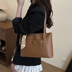 Brown leather tote bag with white contrast stitching and a decorative printed silk scarf