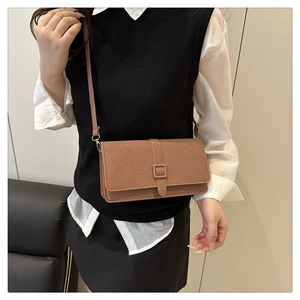 Sac bandoulière marron en tissu texturé avec boucle carrée porté par un mannequin