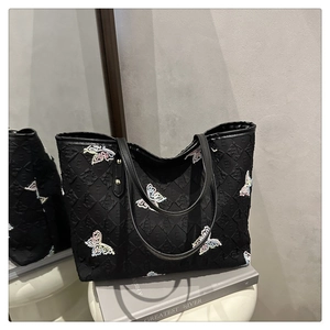Détail du sac cabas noir avec texture matelassée, jacquard de lettres et papillons colorés
