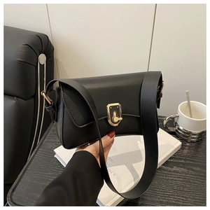 Close-up of minimalist black matte handbag with elegant gold metal lock and wide strap