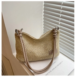Détail du sac à main en paille tressée avec bandoulière en cuir sur un livre ancien