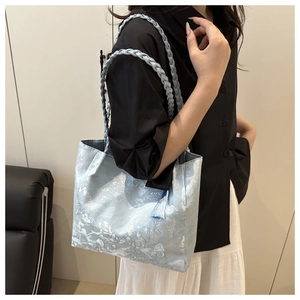 Close-up of light blue jacquard tote bag with lace pattern and woven handles on a model