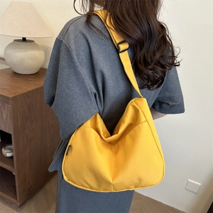 Minimalist yellow half-moon canvas crossbody bag shown on model in cozy home setting