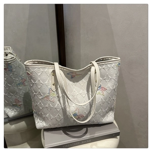 Détail du sac cabas blanc avec texture matelassée et broderies de papillons colorés