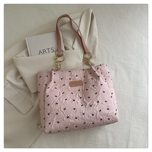 Detail of pink pleated tote bag with black bows and golden metal rings on strap