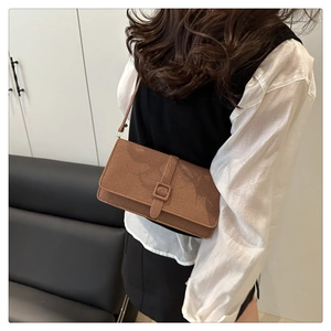 Gros plan d'un sac bandoulière en toile marron avec boucle porté par un mannequin