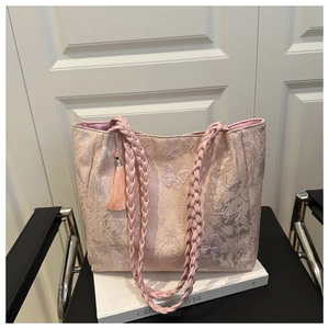 Close-up of pink lace tote bag with butterfly embroidery and braided rope handle