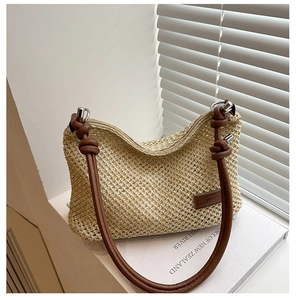 Détail du sac à main en paille tressée avec bandoulière en cuir marron et anneau métallique