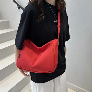 Minimalist red nylon crossbody crescent bag with adjustable wide strap and V-stitch detail