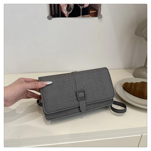Détail du sac à rabat en sergé gris avec boucle carrée texturée et fine bandoulière élégante