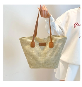Détail du sac cabas tissé avec anses en cuir marron et étiquette de mode chic
