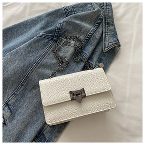 Gros plan d'un sac bandoulière en cuir tressé blanc avec fermoir en métal et chaîne