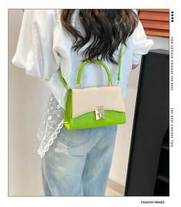 Close-up of contrast color handbag showing green leather stitching and woven texture