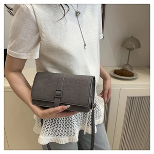 Détail d'un petit sac bandoulière gris en tissu sergé avec rabat et boucle carrée