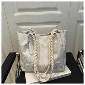 Detail of white lace tote bag featuring butterfly embroidery and woven handles