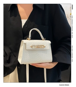 Close-up of white mini Kelly bag featuring crocodile texture and golden metal twist lock