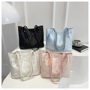 Detailed view of four colors of butterfly embroidered lace tote bags with tassel charms