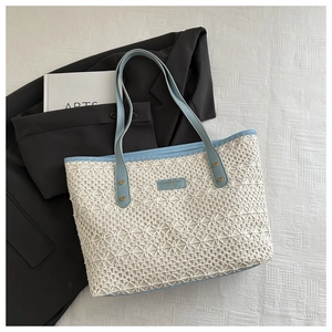 Detail of hollow woven straw tote bag with light blue leather straps and gold rivets