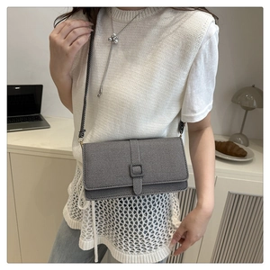 Vue détaillée du sac bandoulière gris texturé sur un bureau avec un ordinateur et une lampe