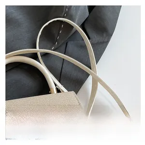 Detailed close-up of woven flap texture with leather strap and gold metal buckle on handbag