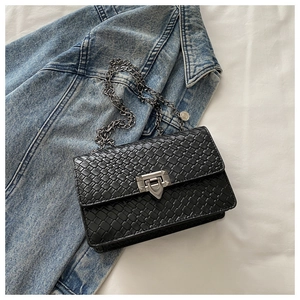 Détail de la texture en cuir tressé noir sur le petit sac avec chaîne argentée