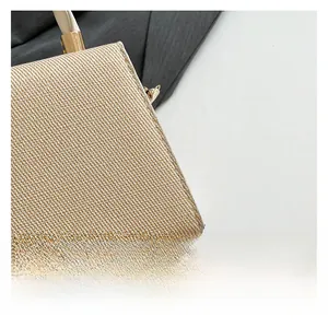 Close-up of beige woven texture and leather handle with gold metal buckle on handbag