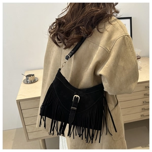 Detail of black suede crossbody bag featuring dense long fringe and metal buckle strap