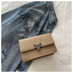 Détail du sac bandoulière beige à texture tressée avec boucle argentée et chaîne