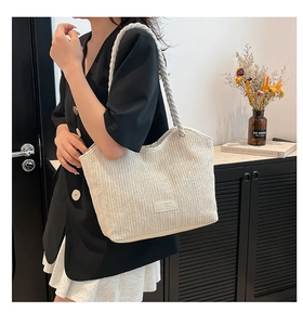 Close-up of beige woven straw tote bag with V-shaped texture and fashion leather tag