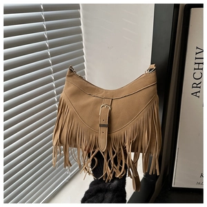 Detail showing the brown suede crossbody bag with long bohemian fringe and metal buckle