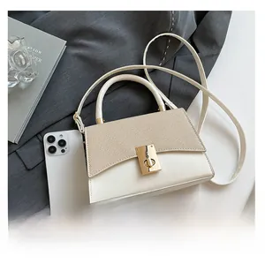 Detail view of mini contrast handbag showing compact size compared to a smartphone