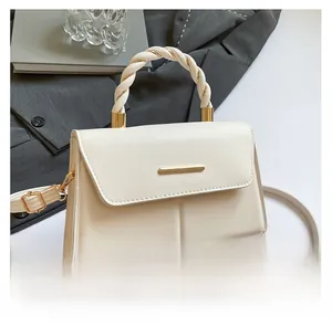 Détail de la poignée tressée et de la barre en métal doré sur le sac bandoulière blanc