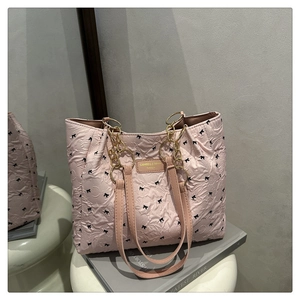 Pink quilted tote bag detail with small black bow pattern and gold chain strap