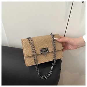Détail du sac beige à texture tressée avec fermoir à rivets et bandoulière en chaîne