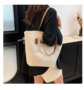Mannequin portant un grand sac cabas tressé crème avec des anses en cuir marron chic