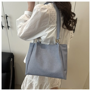 Detail of light blue denim tote bag showing the gold metal rings and thick fabric texture