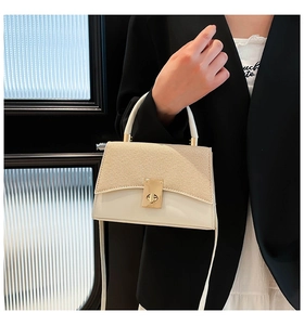 Detail of a chic woven flap on a cream crossbody bag with a gold metal twist lock