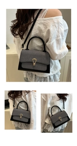 Detail of grey and black crossbody bag showing the golden teardrop metal twist lock