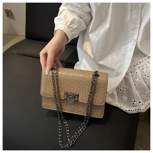 Detail of khaki square crossbody bag featuring woven texture and gunmetal chain strap