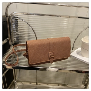 Détail d'un sac bandoulière marron à texture tressée avec une boucle rectangulaire
