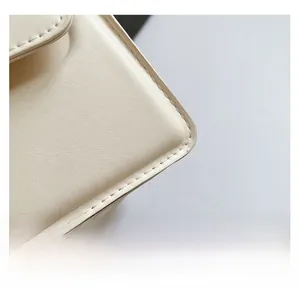 Gros plan sur les coutures blanches et la texture du cuir d'un sac carré minimaliste
