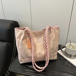Pink lace tote bag with butterfly embroidery and woven handles on a coffee table