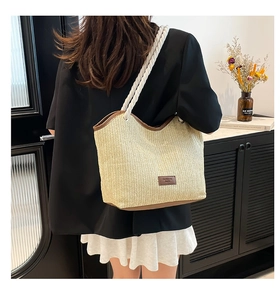 Detailed view of woven straw tote bag with brown leather trim and cotton rope handles
