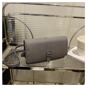 Détail du sac bandoulière en tissu gris posé sur un support en acrylique moderne