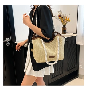 Detail of straw tote bag with brown leather trim and white cotton rope handles