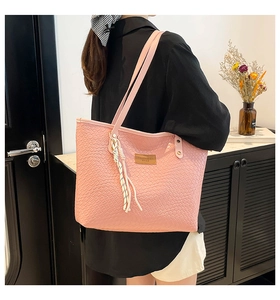 Gros plan d'un sac cabas tressé rose avec étiquette en cuir et accessoire de corde tressée