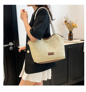 Detail of a large straw tote bag with brown trim and sturdy cotton rope handles