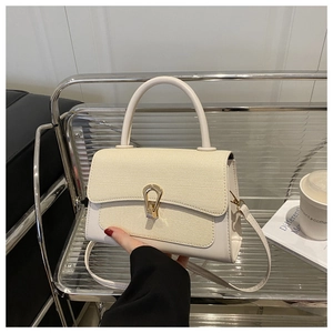 Detail of cream crossbody bag showing woven texture flap and gold horseshoe buckle